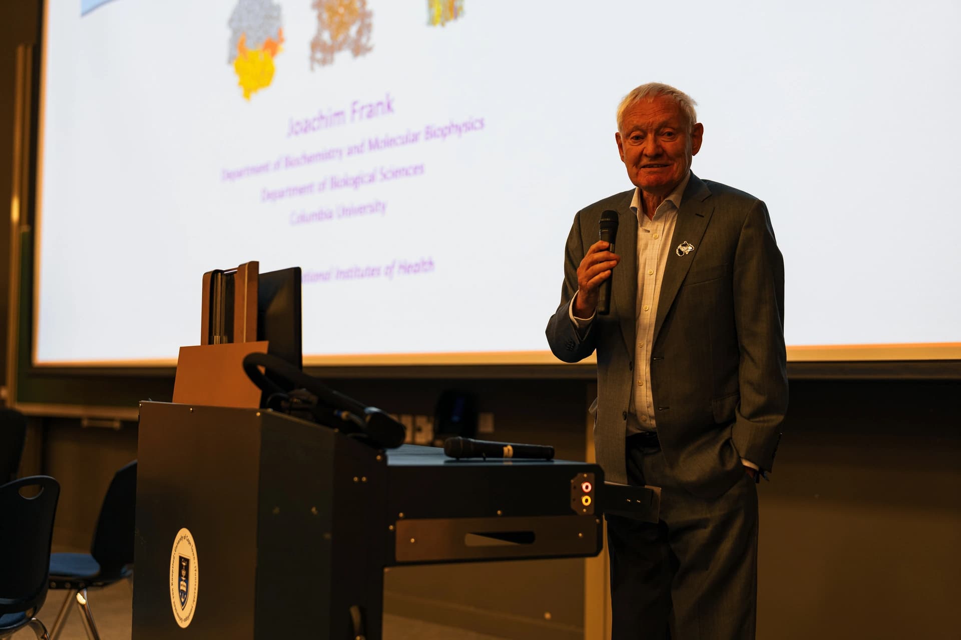 Nobel Laureate Prof. Joachim Frank speaking with a microphone beside a UCT lecture podium