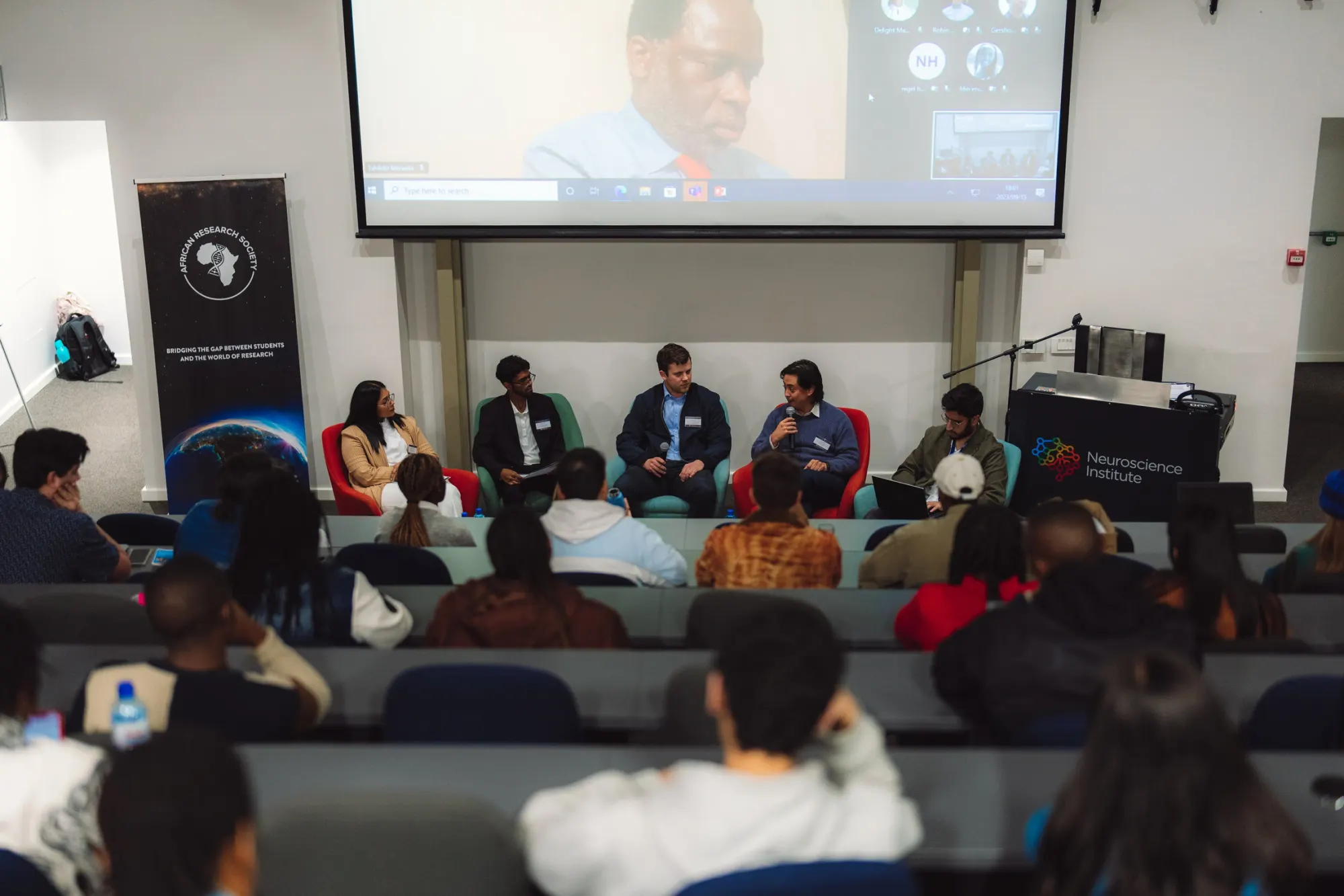 A five-person panel taking questions from a full lecture theatre beside an ARS banner